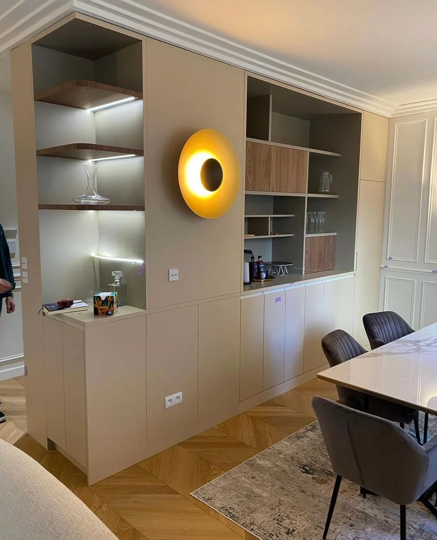 Agencement de séjour sur mesure avec niches éclairées, étagères en bois et applique dorée