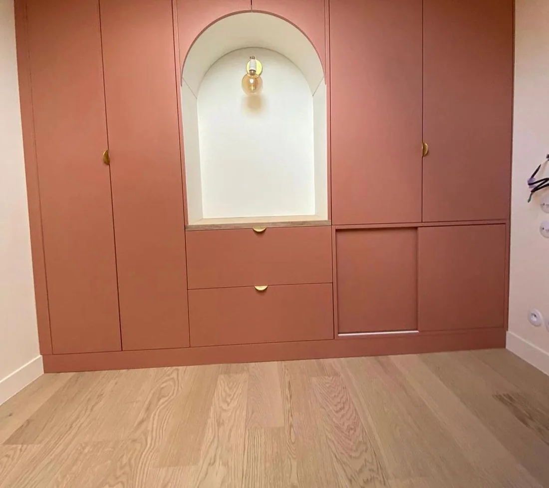 Mur de rangements terracotta toute hauteur avec niche en arche et parquet clair
