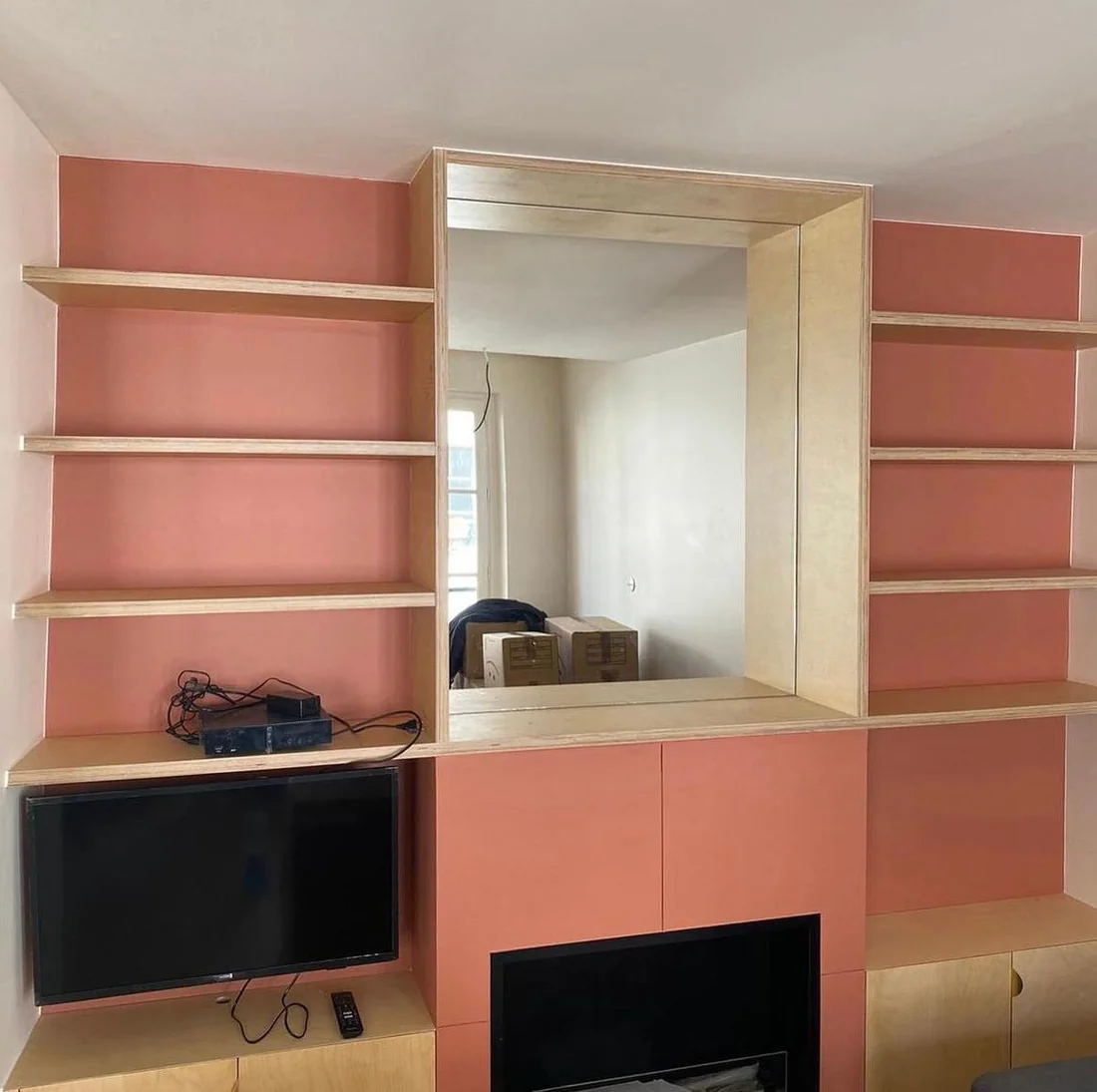 Meuble télévision sur mesure rose avec étagères et grand miroir encadré de bois clair