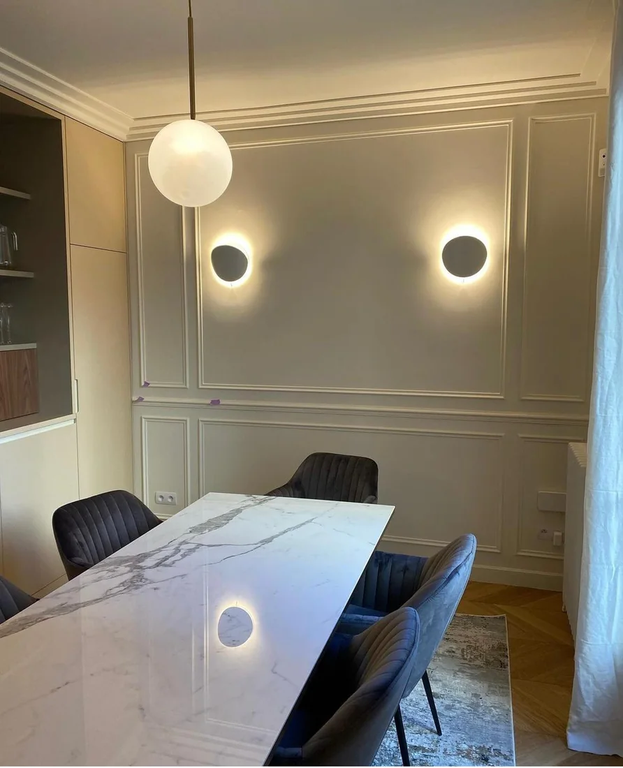 Salle à manger avec moulures peintes ton sur ton, table en marbre et appliques rondes