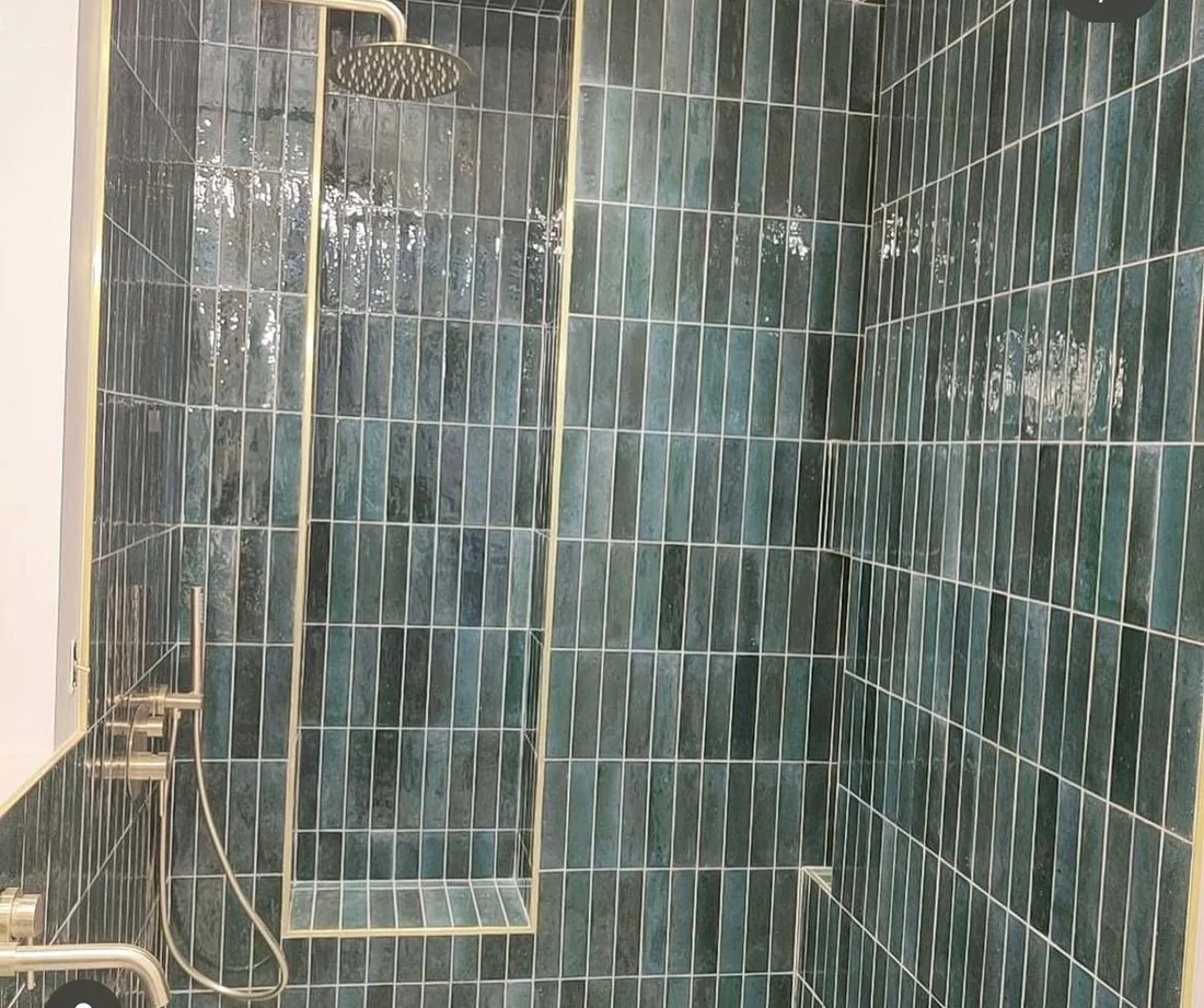 Douche à l'italienne habillée de zellige vert vertical, robinetterie laiton et paroi encadrée