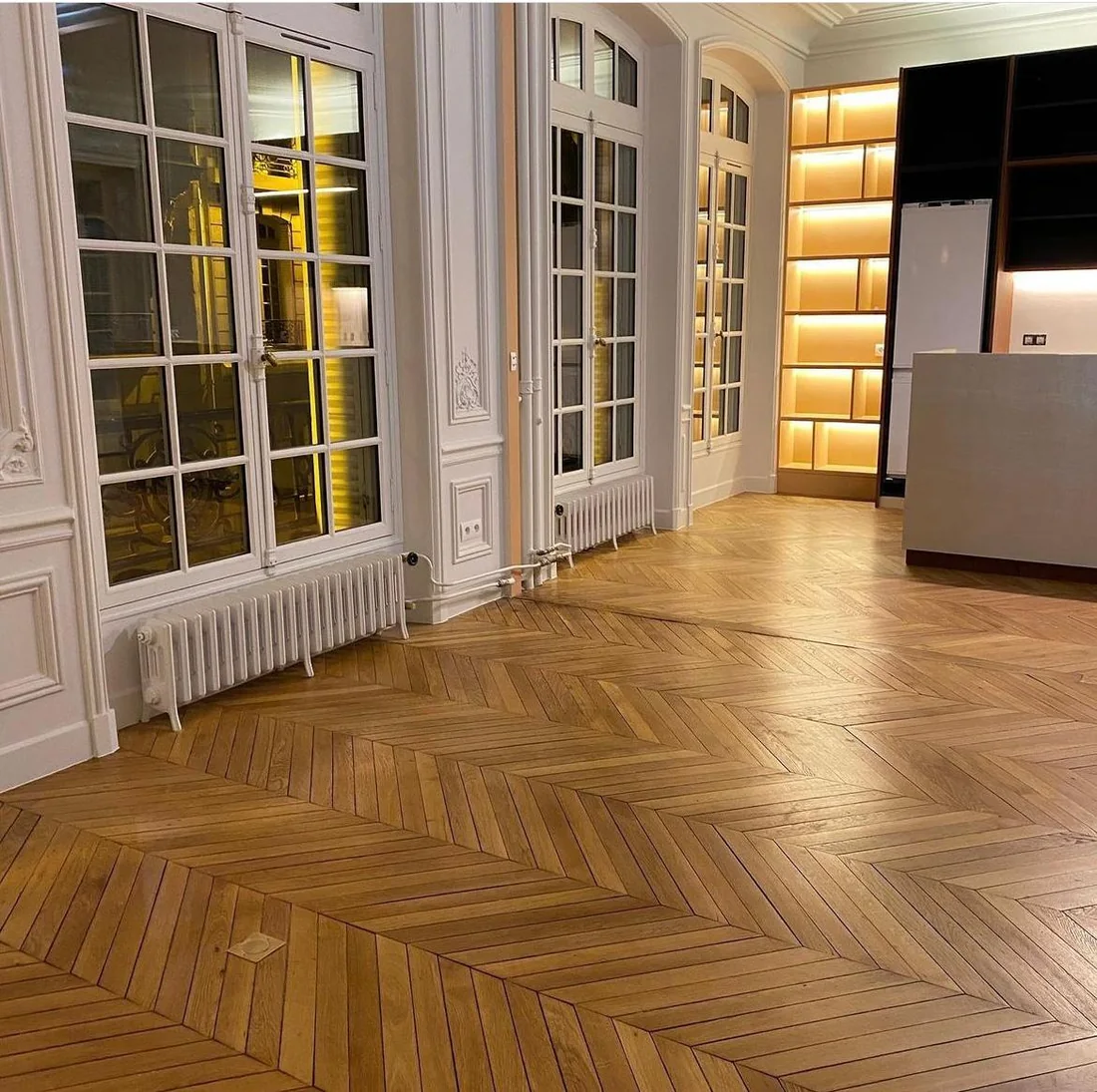 Séjour haussmannien avec parquet en point de Hongrie, portes vitrées et rangements éclairés